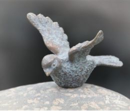 Bronzen vogeltje op grafsteen