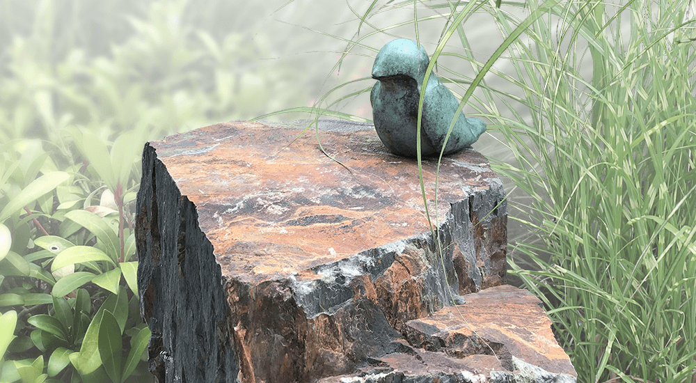 natuurlijke urn zwerfkei met bronzen vogeltje